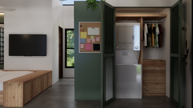 Interior of a modern bedroom with a wall-mounted TV, a corkboard with colorful notes, a washer and dryer set, wooden furniture, and green louvered closet doors.