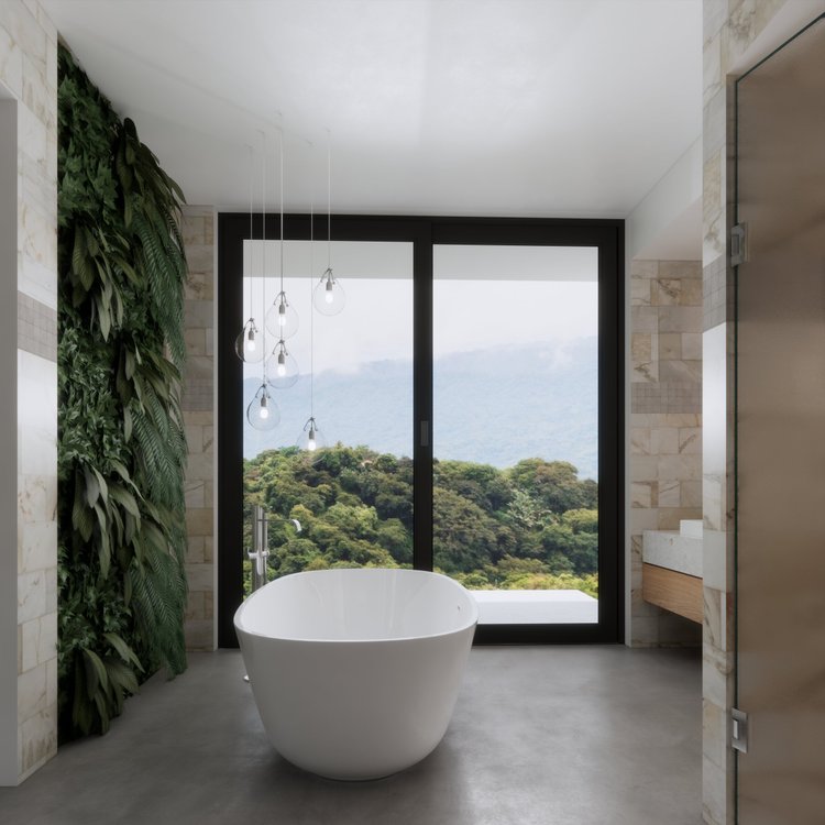 Modern bathroom with a freestanding bathtub facing large glass doors that reveal a lush green landscape with mountains in the distance, a vertical green plant wall on the left, and a cluster of hanging light bulbs.