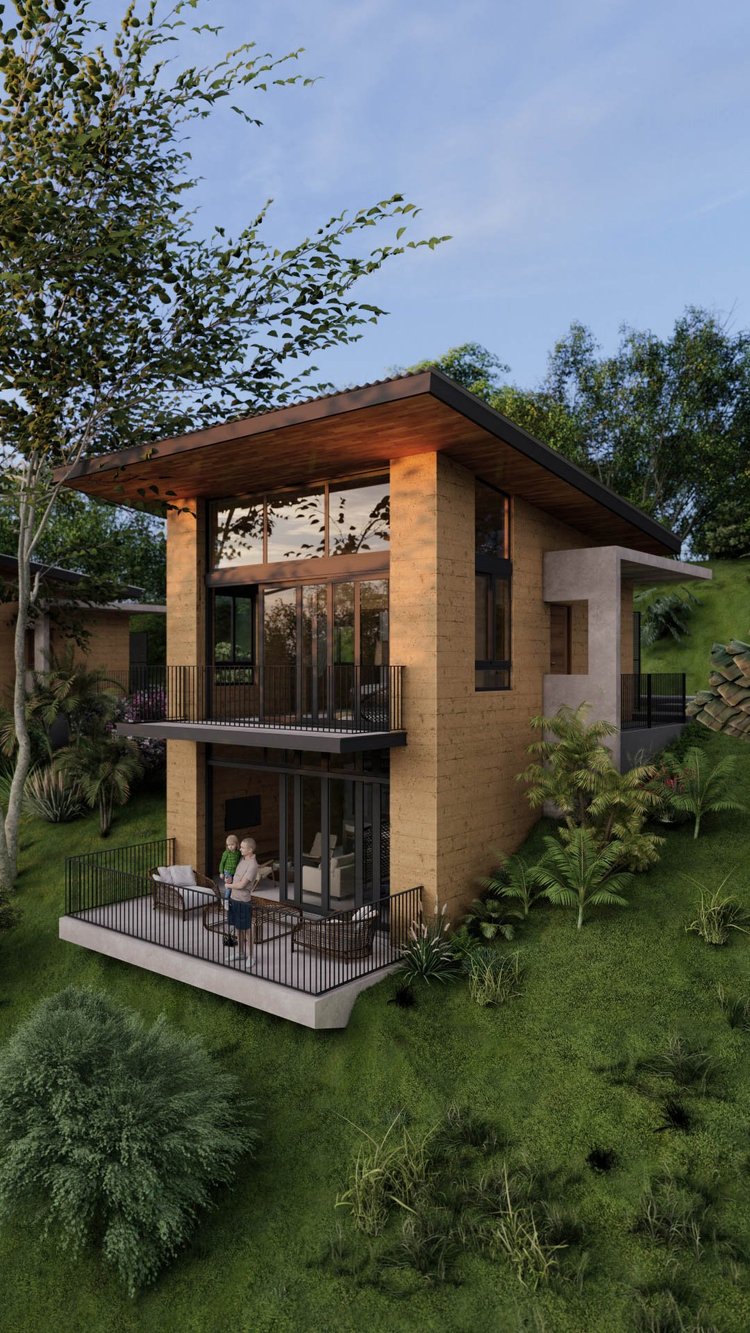 Modern two-story house with a balcony and patio, surrounded by trees and greenery, with two people standing on the patio.