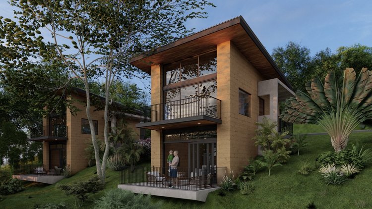 Modern two-story house with large glass windows, surrounded by lush greenery and trees, featuring a balcony and outdoor patio area with seating.